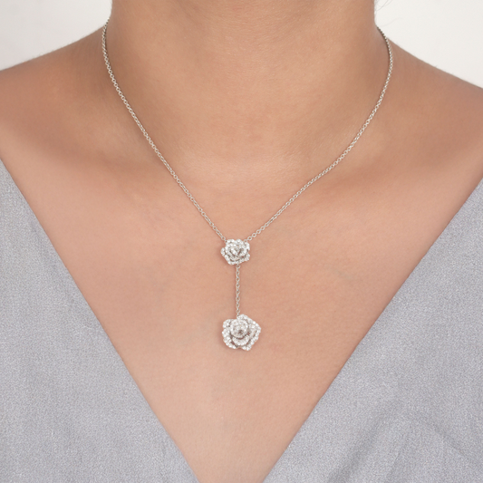 Silver necklace with rose-shaped pendants on a person wearing a gray top.