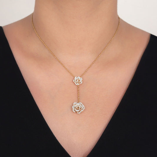 Gold necklace with floral pendants on a person wearing a black top.