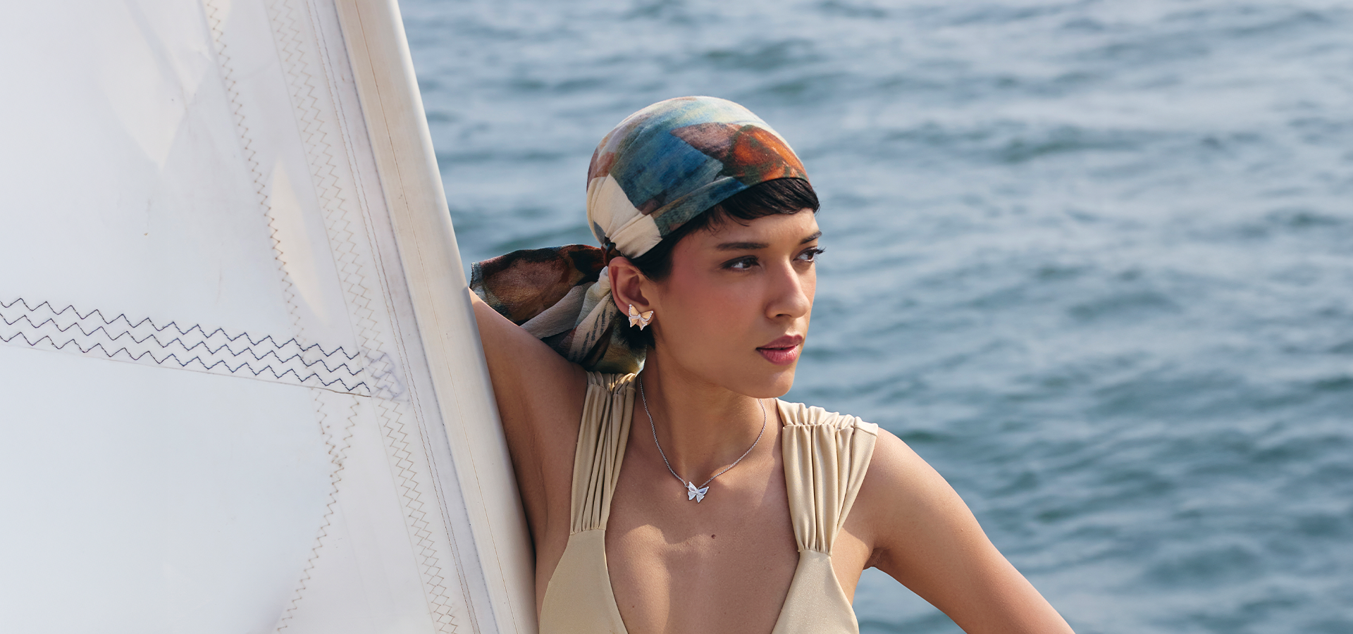 Woman with a colorful headscarf on a sailboat with ocean in the background
