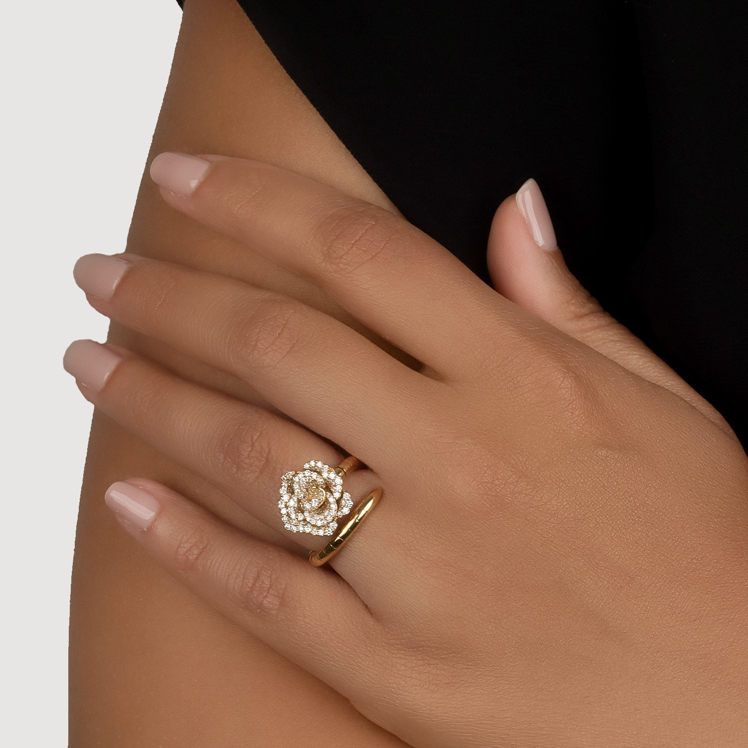 Gold ring with a diamond design on a hand against a neutral background